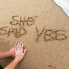 two people are writing in the sand with their hands on top of eachother