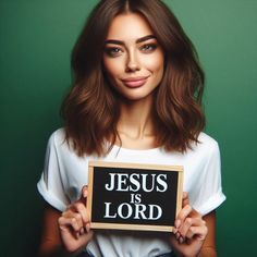 a woman holding a sign that says jesus is lord in front of her face, against a green background