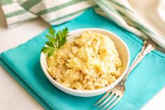 a white bowl filled with mashed potatoes on top of a blue napkin