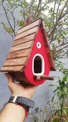 a hand holding up a birdhouse made out of wood