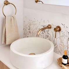 a white sink sitting under a bathroom mirror next to a towel rack and soap dispenser