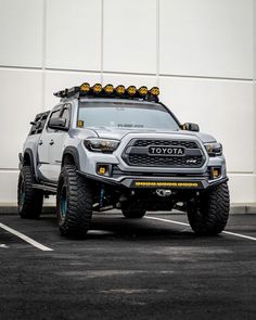 a white toyota truck parked in a parking lot next to a building with yellow lights on top