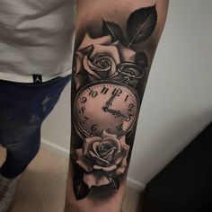 a black and white photo of a clock with roses on it's arm,