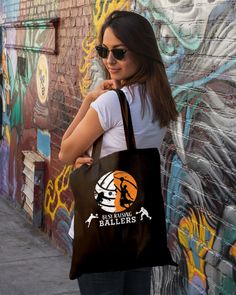 a woman is standing in front of a wall with graffiti on it holding a brown bag