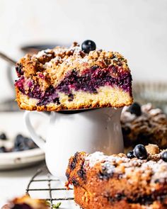 blueberry crumb cake on a cooling rack with one slice taken out and the rest of the cake in the background