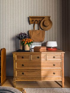 a wooden dresser sitting next to a wall with a hat on top of it