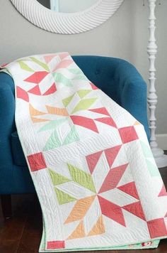 a blue chair with a quilt on it and a mirror in the corner behind it