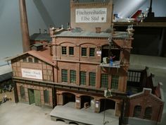 a model of a building with people standing on the roof and in front of it