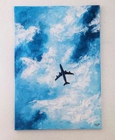 an airplane is flying in the sky above some clouds and blue paint on a white wall