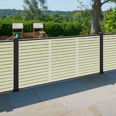 a white and black metal fence on top of a stone floor next to a tree