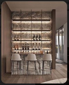 a bar with three stools in front of it and several bottles on the wall