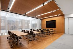 an empty room with tables and chairs in front of a flat screen tv on the wall