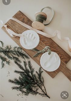 two white plates with handprints on them next to some ribbon and pine branches