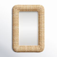 a mirror made out of wicker with a white wall in the background and a light brown frame