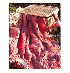 a pink crocheted blanket sitting on top of a table next to some flowers