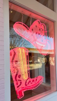 a neon sign is in the window of a store that has pink shoes on display