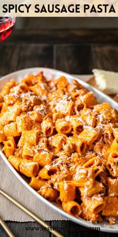 a pasta dish with meat and sauce in a white bowl on a wooden table next to some bread