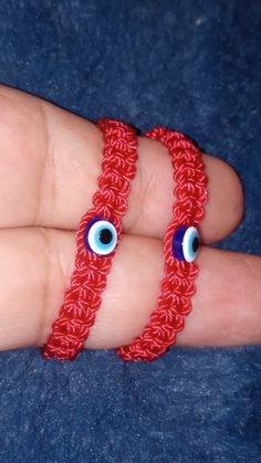 two red bracelets with blue eyes are on someone's hand