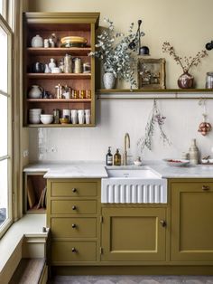 a kitchen with green cabinets and white counter tops