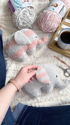 a woman is sitting on the floor next to crocheted elephants and knitting supplies