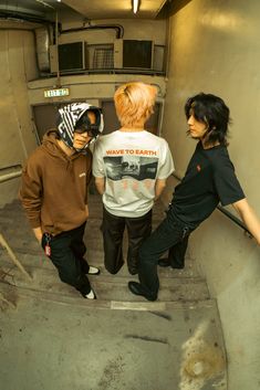 three young men standing on the stairs in a skateboard facility, one wearing a helmet