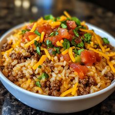 a close up of a bowl of food with rice and cheese on the top,