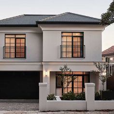 a white two story house with black garage doors