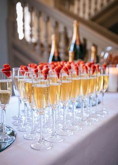 several glasses filled with champagne and strawberries on a table