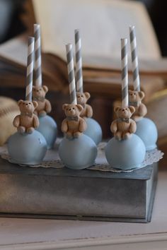 there are four candles that have been placed on top of blue balls with teddy bears