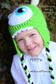 a young boy wearing a green crocheted hat with an eyeball on it