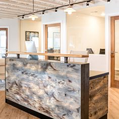 an office with wood flooring and white walls is pictured in this image, the front desk has a laptop on it