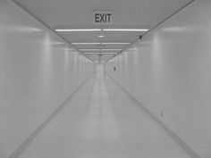 an empty hallway with exit sign in black and white