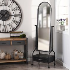 a large mirror sitting on top of a wooden floor next to a shelf with drawers