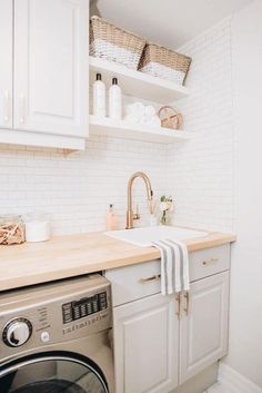 a washer and dryer in a small room with white walls, cabinets, and open shelving