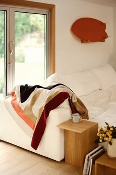 a white couch sitting in front of a window next to a table with a cup on it