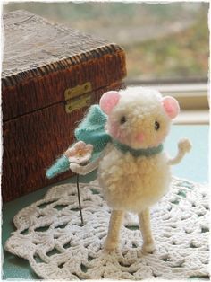 a small stuffed animal standing on top of a doily next to a wooden box