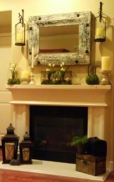 a fireplace with candles and flowers on it in front of a mirror over the mantel