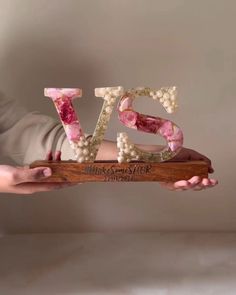 a person holding up the word love made out of beads and wood in their hands