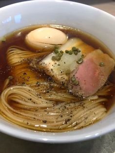 a white bowl filled with noodles and meat