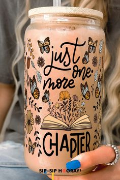 a woman is holding a glass with a book on it that says just one more chapter