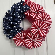 an american flag wreath is hanging on the door with red, white and blue bows