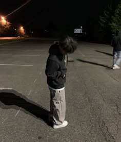 two people standing in an empty parking lot at night