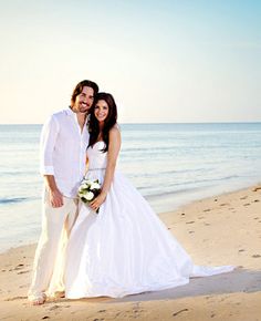 a bride and groom posing on the beach for a wedding photo with the ocean in the background