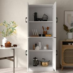 a white book shelf with pots and pans on it in a living room next to a table