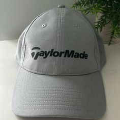 a gray taylor made hat sitting on top of a white table next to a potted plant