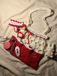 a crocheted purse sitting on top of a bed next to a teddy bear