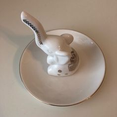 a small white rabbit figurine sitting on top of a plate