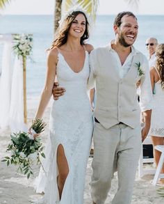 a newly married couple walking down the beach