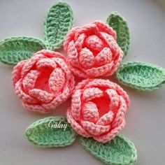 three crocheted flowers with leaves on them