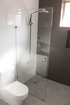 a white toilet sitting next to a walk in shower